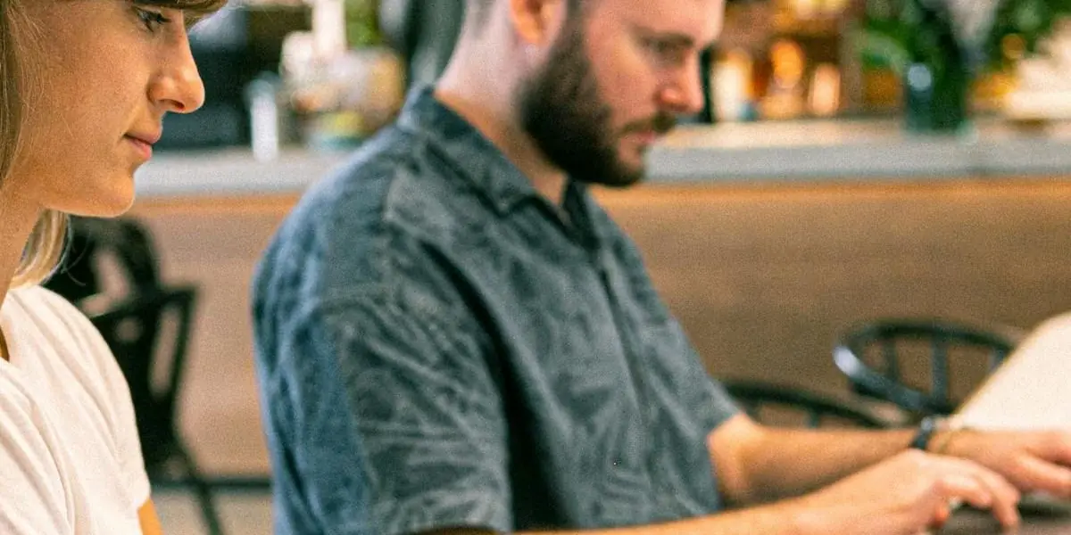 Eine Frau und ein Mann arbeiten in einem Café nebeneinander an ihren Laptops